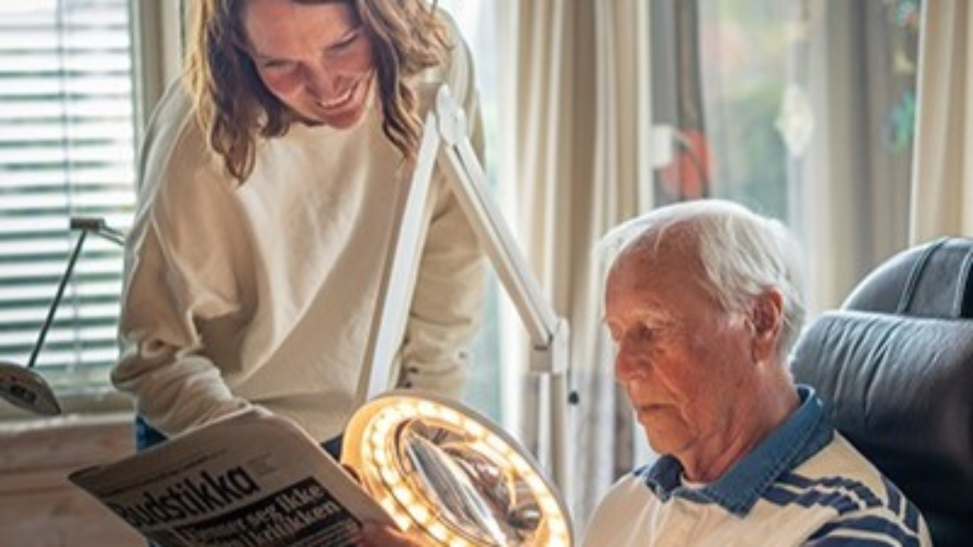 Mann som får hjelp av en lupe-lampe for å lese avisen