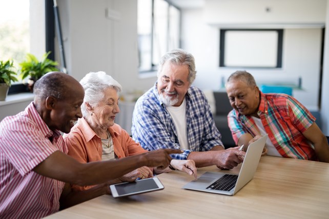 gruppe av eldre som sitter samlet foran en laptop