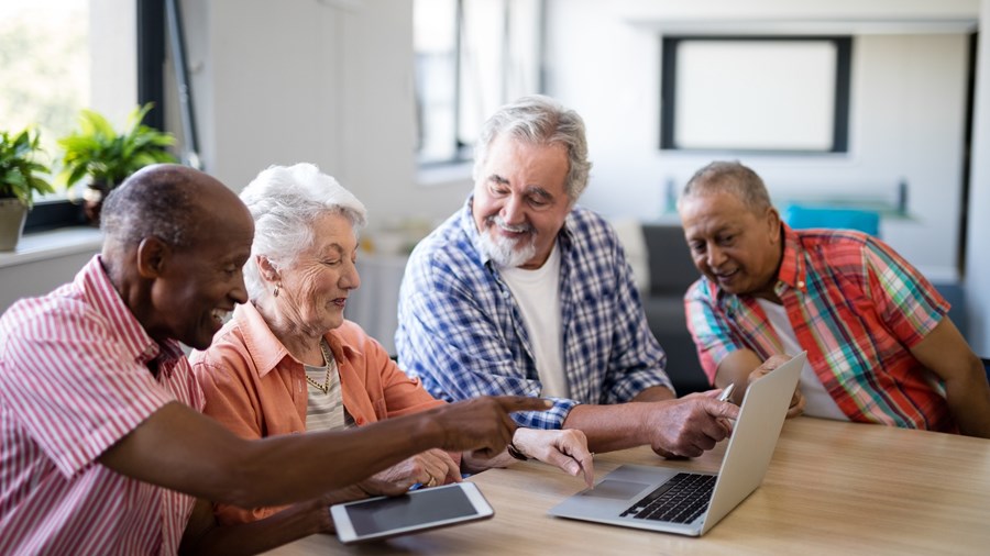 gruppe av eldre som sitter samlet foran en laptop