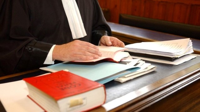 rød lovbok i ytterkant av bilde, og deler av dommerkappe i bakgrunnen