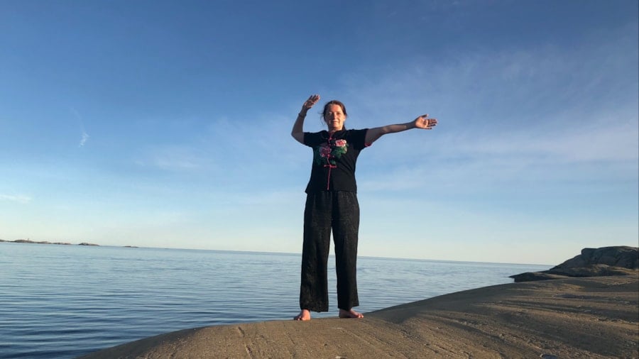 Kvinne som trener qigong ved havet