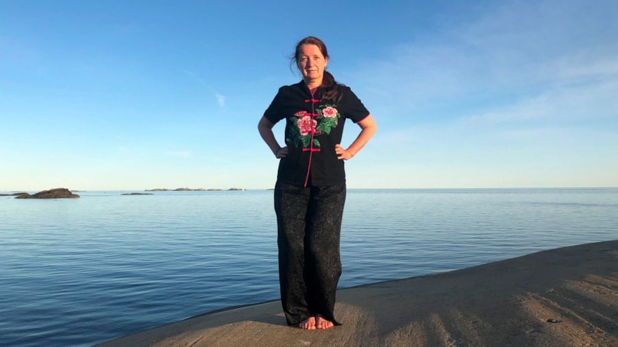 Kvinne som trener qigong ved havet