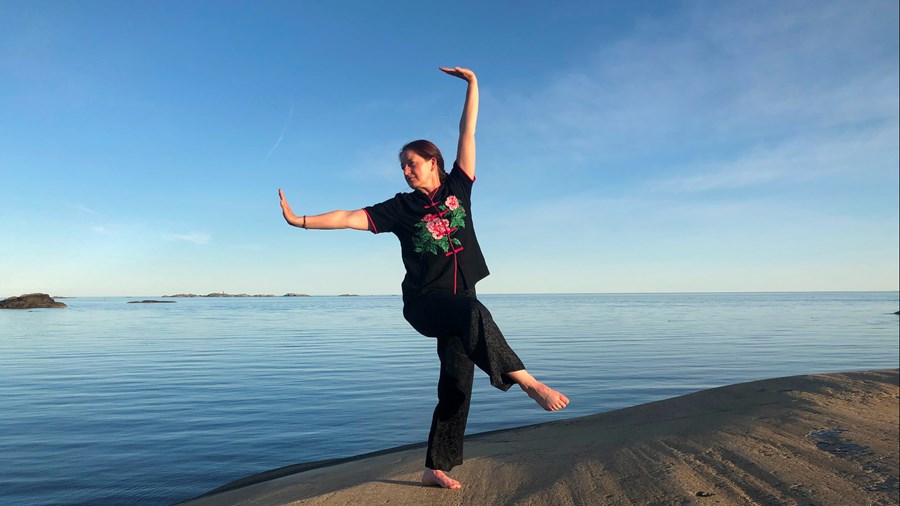 Kvinne som trener qigong ved havet