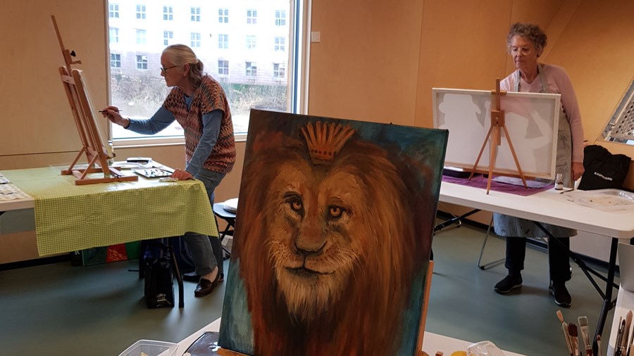 2 damer som maler, og er maleri av en løve.
