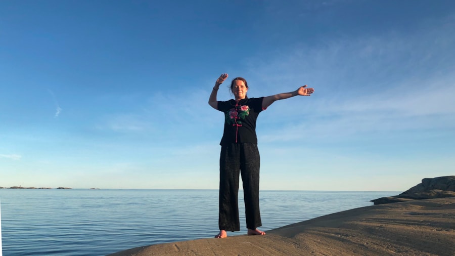 Kvinne som trener qigong ved havet