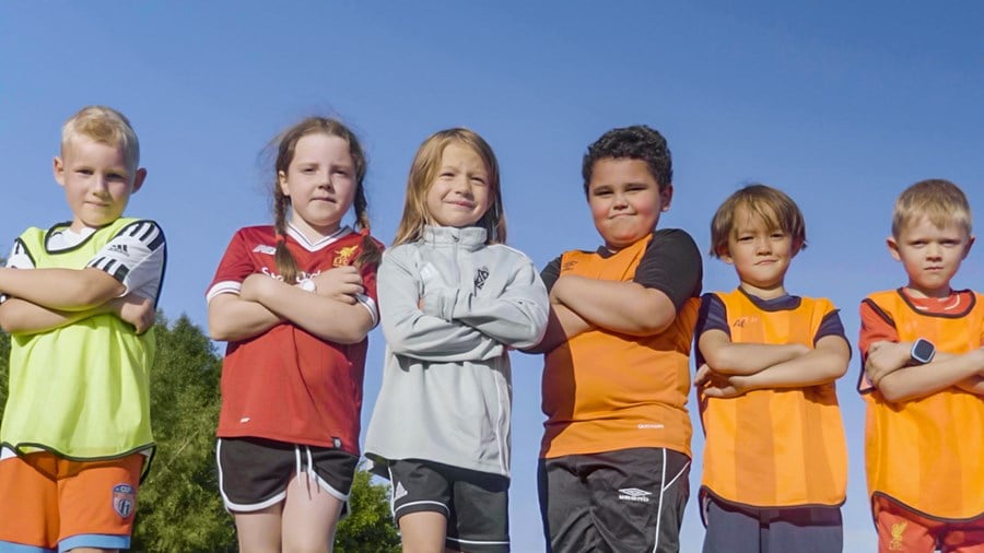 Seks småskolebarn som står oppstilt som fotballag
